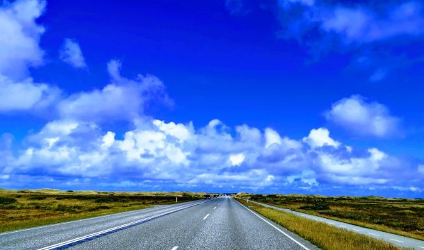 Eine leere Straße unter einem blauen Himmel mit Wolken.
