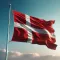Die Flagge Dänemarks weht vor einem klaren blauen Himmel mit leichten Wolken.