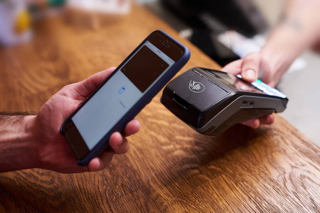 Eine Person hält ein Telefon, während eine andere Person eine Kreditkarte hält.
