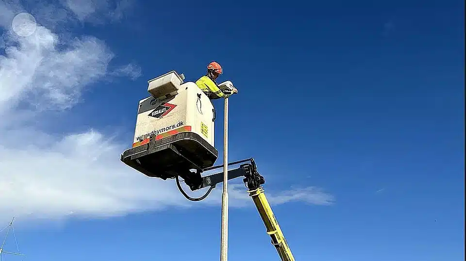 Ein Mann, der an der Spitze einer Stange arbeitet.