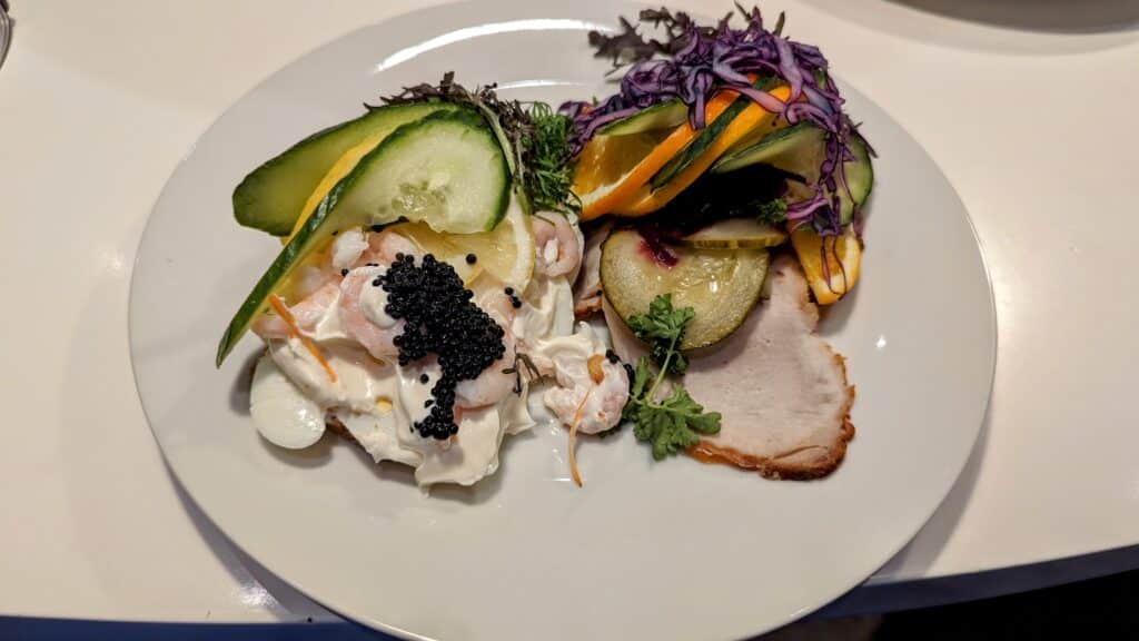 Ein weißer Teller mit einem Sandwich und Gemüse darauf.